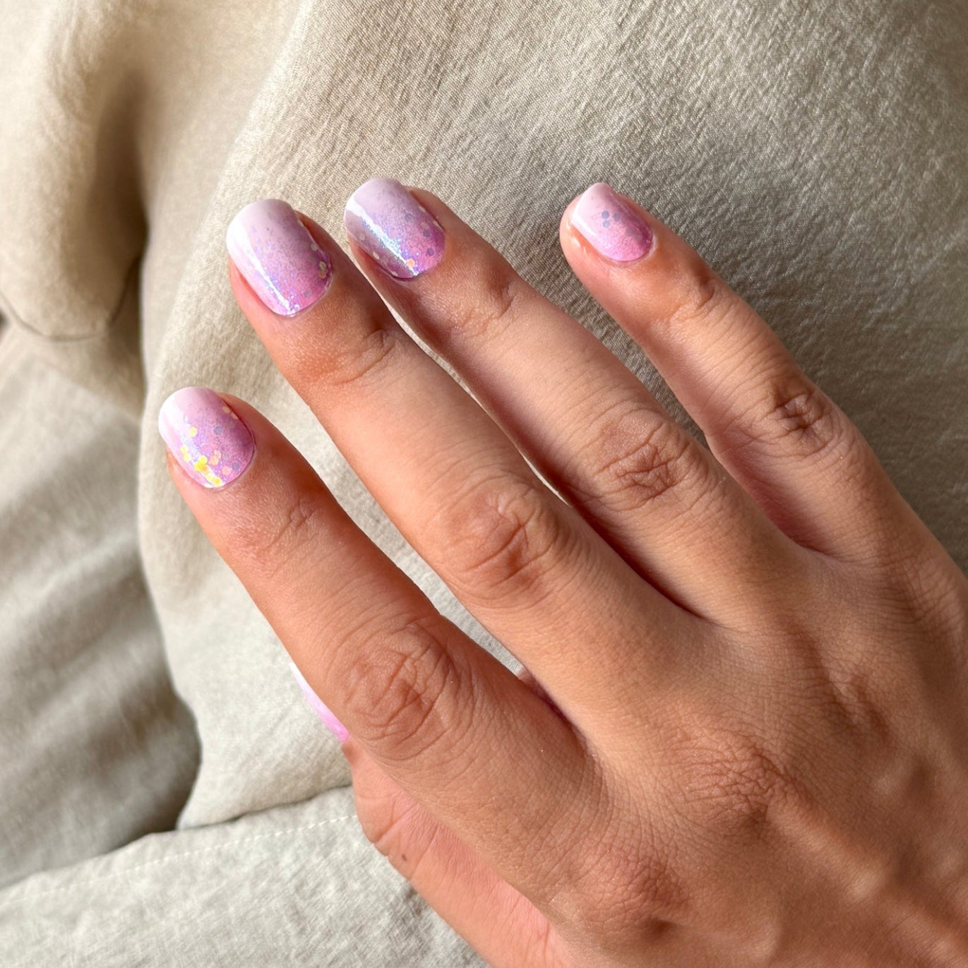 Close-up of a hand with pink Cherry blossom inspired nail wraps by namora on a neutral background