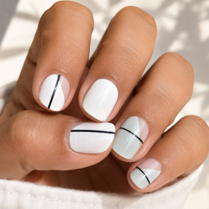Hand with white nails featuring black lines on a light background