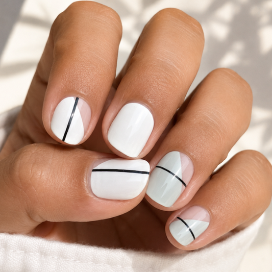 Hand with white nails featuring black lines on a light background