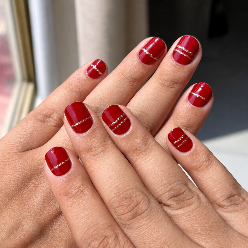 Close-up of a hand with red nail wraps on a blurred background
