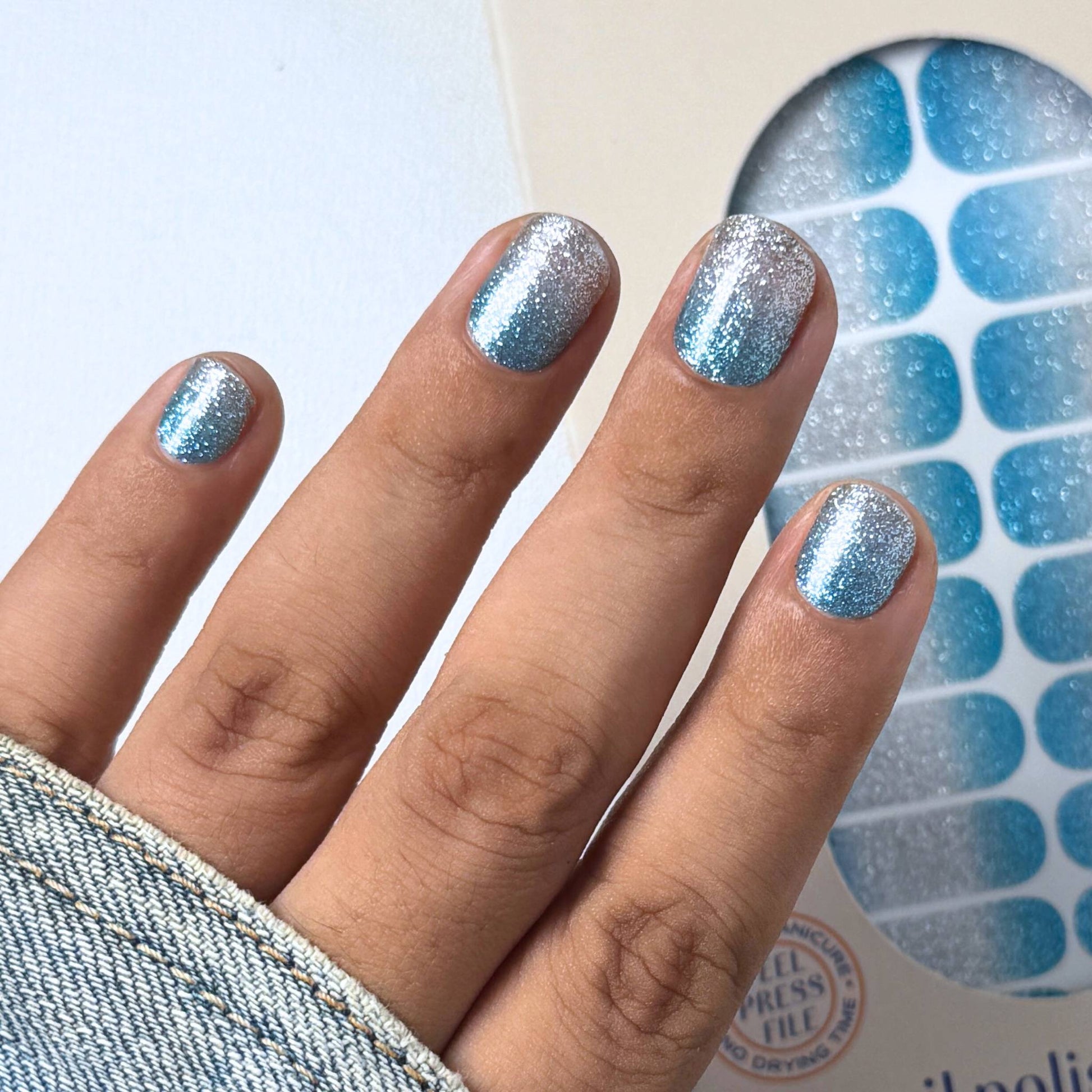 Hand with blue silver glittery nail wraps 