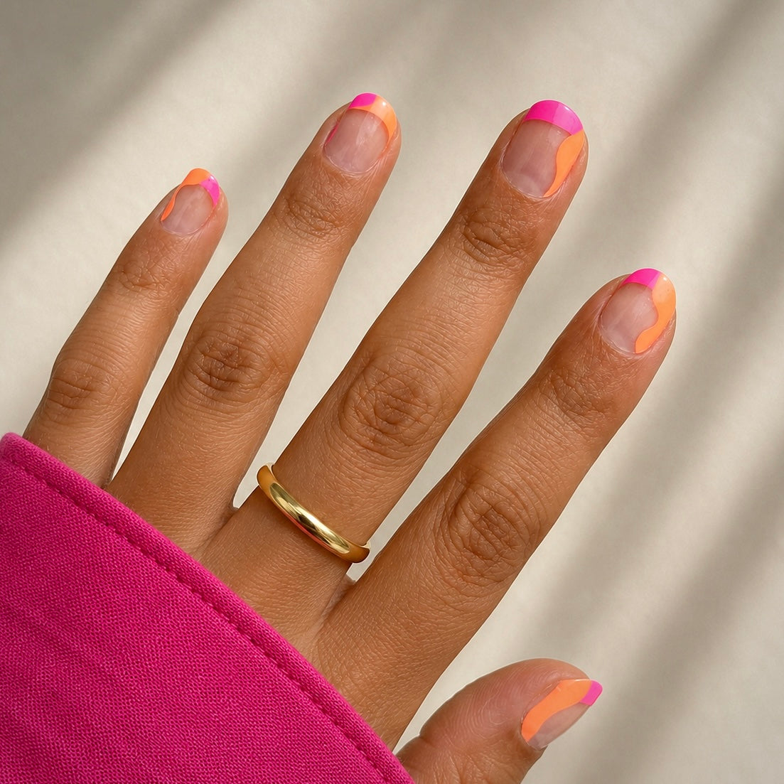 Hand with pink and orange french tips wearing Lola by namora 