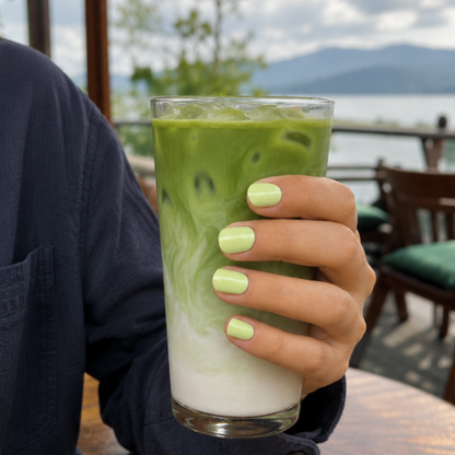 Person holding a green matcha drink and showing her green matcha nails
