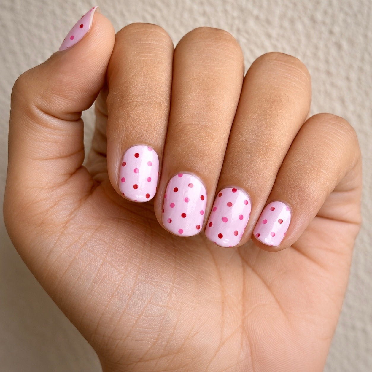 Hand wearing pink & polka nail wraps by namora