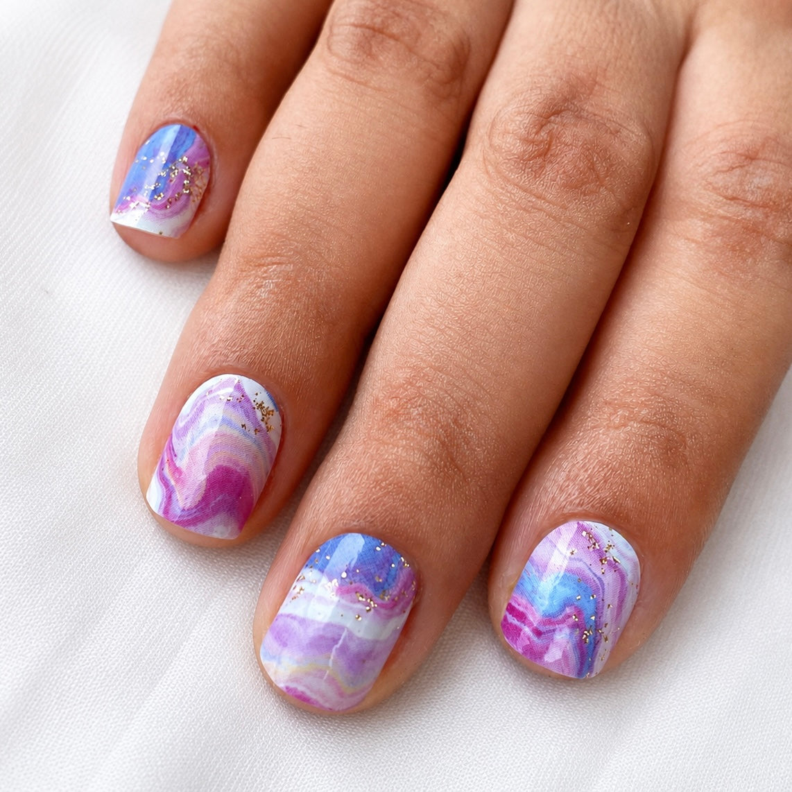 Hand wearing ink galaxy nail wraps by Namora