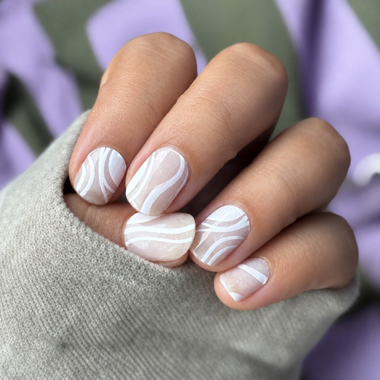 Close-up of a hand with marbleized nail design on a blurred background